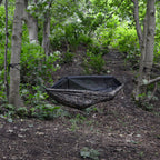 DD Frontline Hammock i Multicam hengt opp mellom to trær i en grønn løvskog, med myggnettet lukket