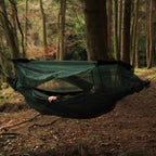 Person som ligger i en hengekøye med DD Hammock Mosquito Net rundt, i skogen
