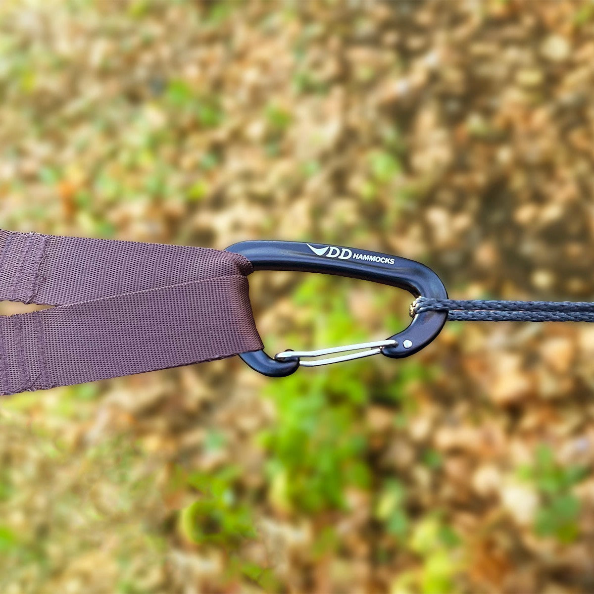 Nærbilde av en DD-karabiner som kobler en brun trestropp til en tynn slynge