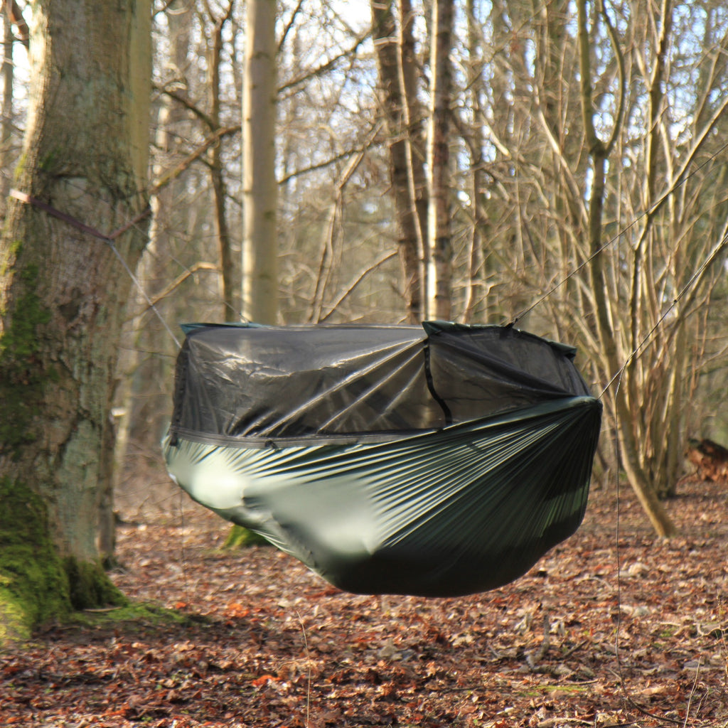 DD SuperLight Frontline Hammock med lukket myggnett mellom to trær i løvskog