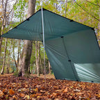 DD Tarp XL i Olivengrønn satt opp med én stang foran og den ene siden ned mot bakken, i en høstskog
