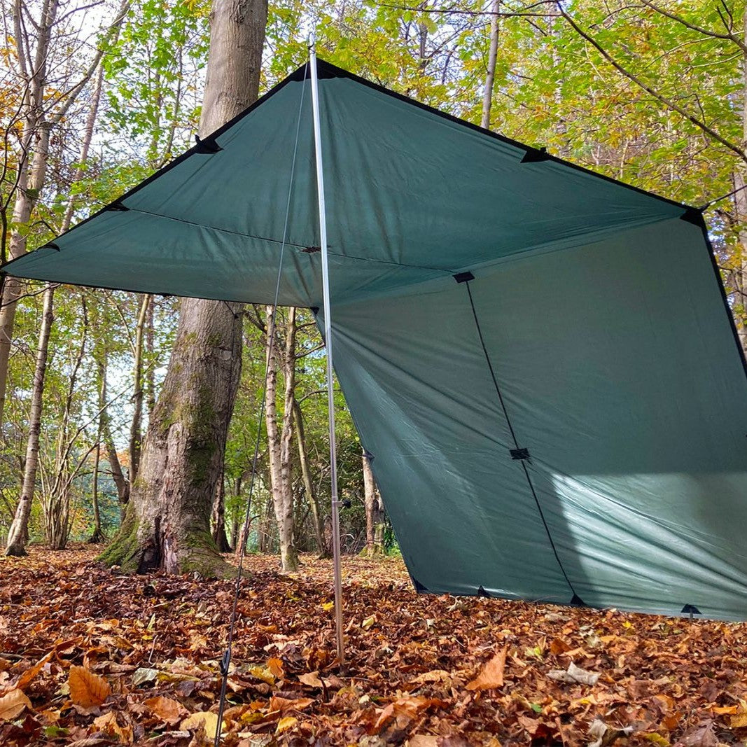 DD Tarp XL i Olivengrønn satt opp med én stang foran og den ene siden ned mot bakken, i en høstskog