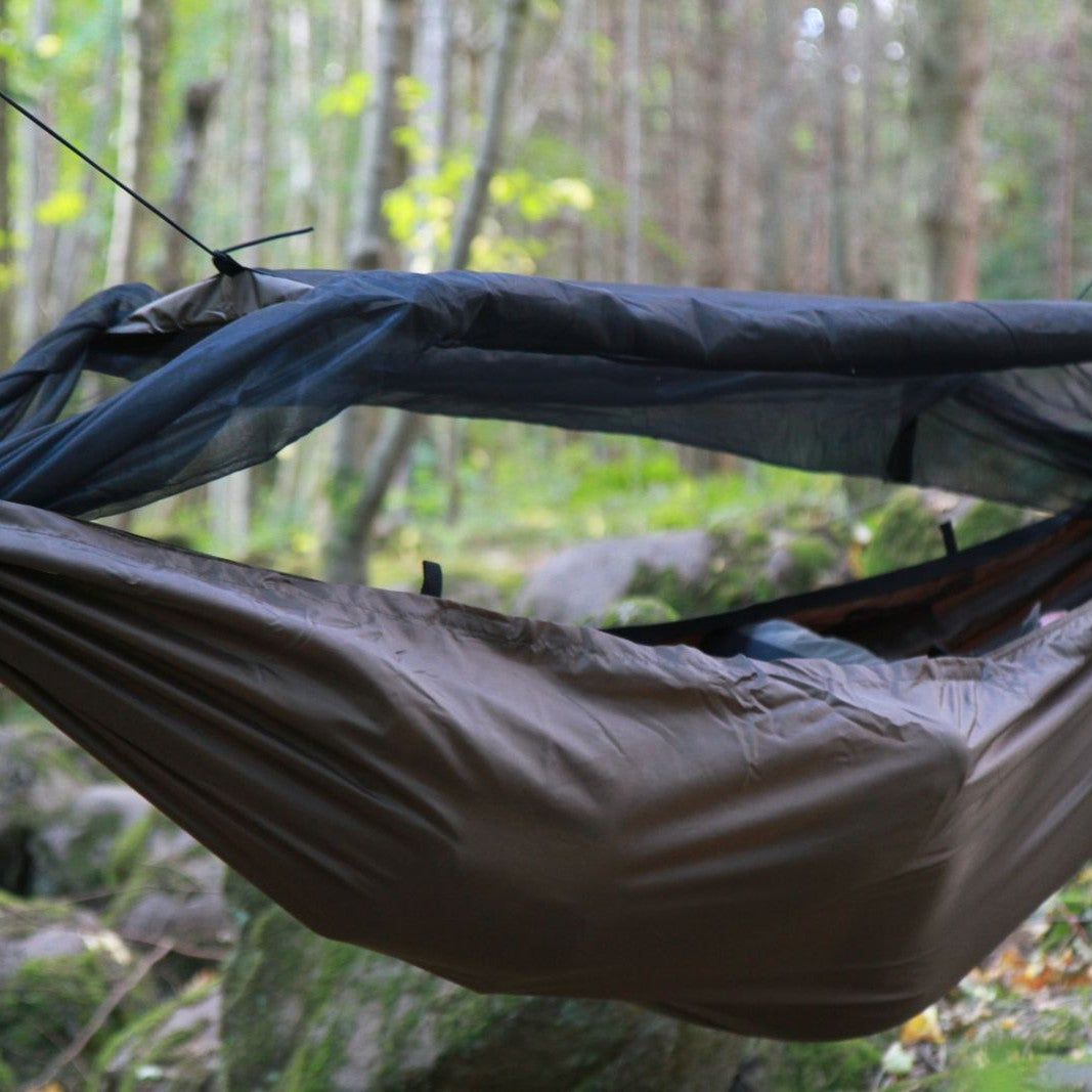 Brun DD Travel Hammock / Bivi med myggnett hengt opp mellom trær i skogen